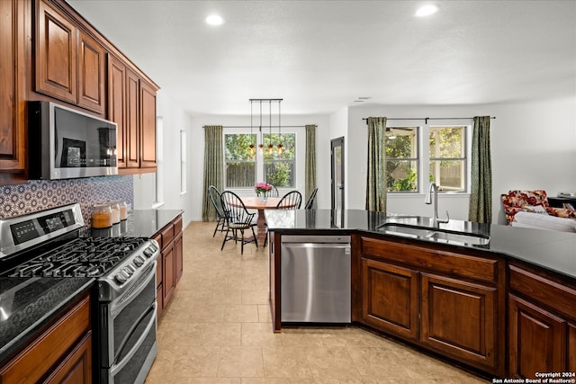 kitchen featuring a wealth of natural light, sink, decorative light fixtures, and appliances with stainless steel finishes