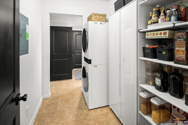 laundry room with electric panel and stacked washer / drying machine