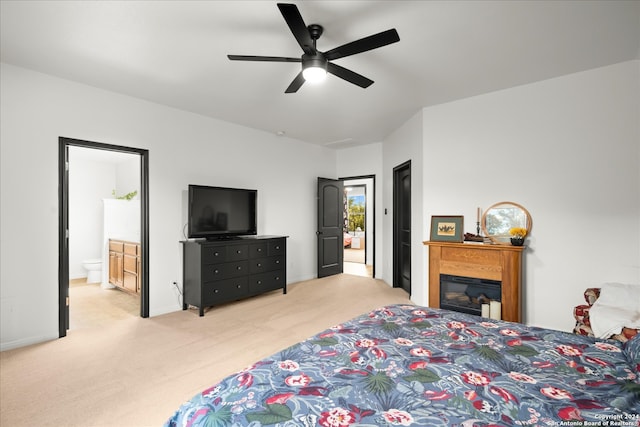 bedroom with connected bathroom, light colored carpet, and ceiling fan