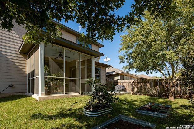 back of property with a sunroom, a yard, and ceiling fan