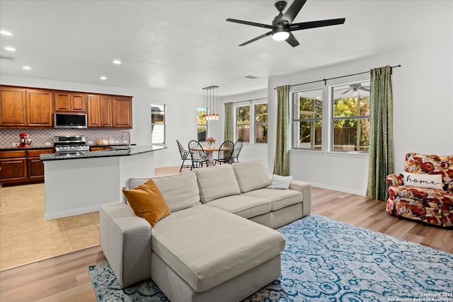 living room featuring ceiling fan, sink, and light wood-type flooring