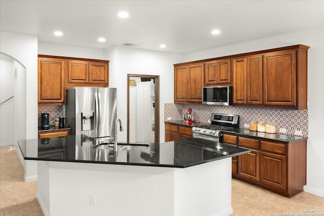 kitchen featuring a kitchen island with sink, appliances with stainless steel finishes, sink, and tasteful backsplash