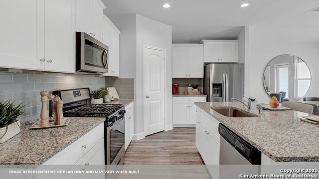 kitchen featuring stainless steel appliances, white cabinetry, sink, and a kitchen island with sink