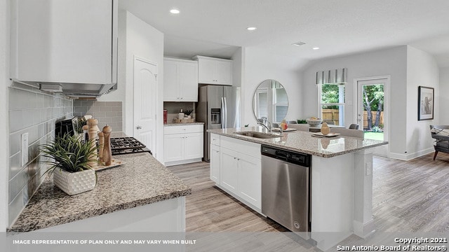 kitchen featuring a kitchen island with sink, appliances with stainless steel finishes, white cabinets, and light stone counters