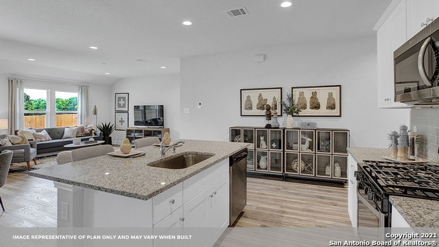 kitchen with stainless steel appliances, light stone countertops, white cabinets, and sink