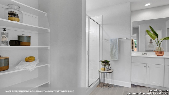 bathroom featuring walk in shower, vanity, and hardwood / wood-style flooring