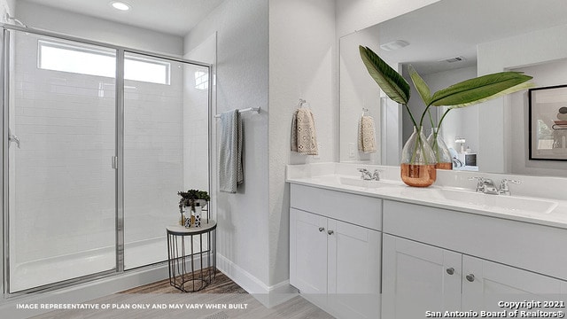 bathroom featuring vanity, hardwood / wood-style flooring, and a shower with door