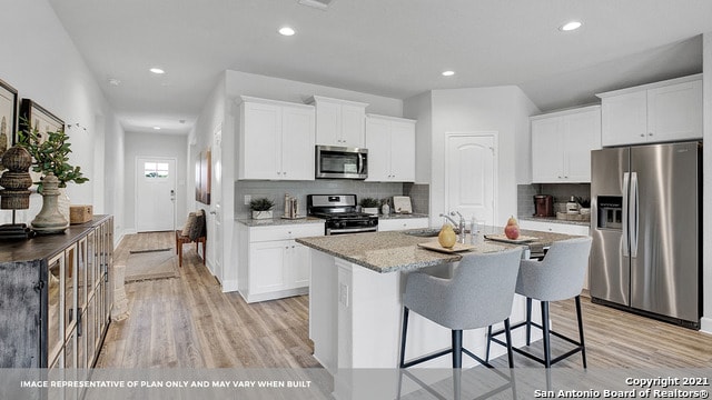 kitchen featuring light hardwood / wood-style flooring, white cabinetry, decorative backsplash, and stainless steel appliances