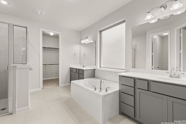 bathroom with a stall shower, two vanities, a sink, and a bath