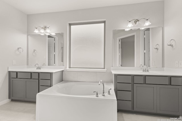 bathroom with a sink, tile patterned flooring, two vanities, and a bath