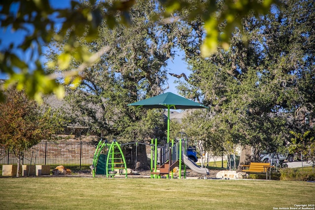 community play area featuring a lawn and fence