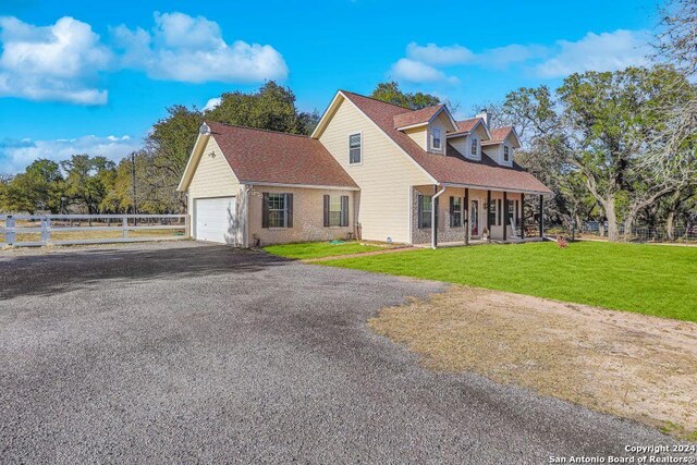 exterior space with a garage, covered porch, and a front yard