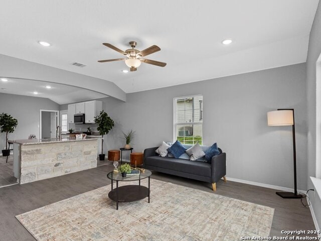 living room featuring lofted ceiling, dark wood-type flooring, and ceiling fan