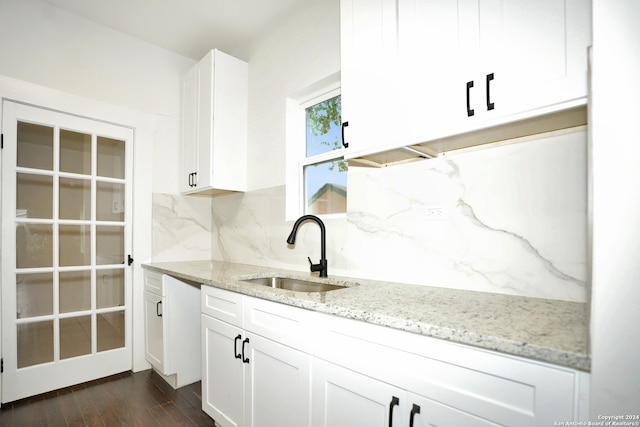 kitchen with white cabinetry, sink, light stone counters, tasteful backsplash, and dark hardwood / wood-style flooring