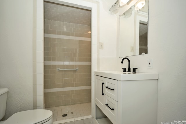 bathroom featuring vanity, toilet, and tiled shower