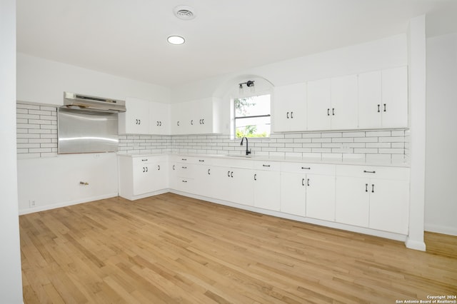 kitchen featuring white cabinetry, light wood-type flooring, sink, and tasteful backsplash