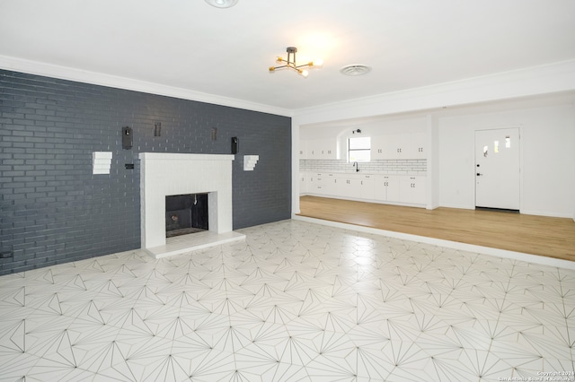 unfurnished living room with sink, brick wall, and crown molding