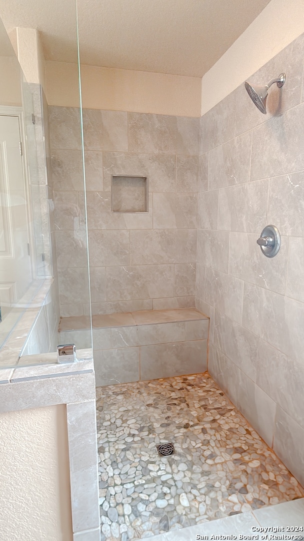 bathroom with tiled shower and a textured ceiling