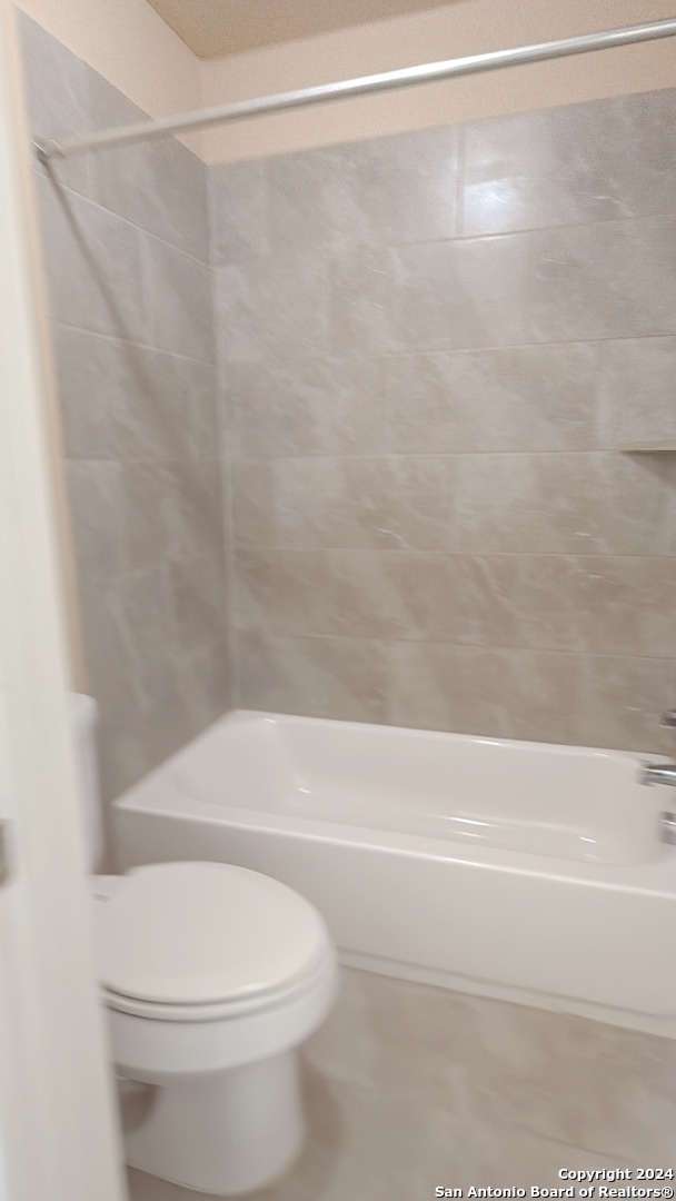 bathroom featuring tiled shower / bath and toilet