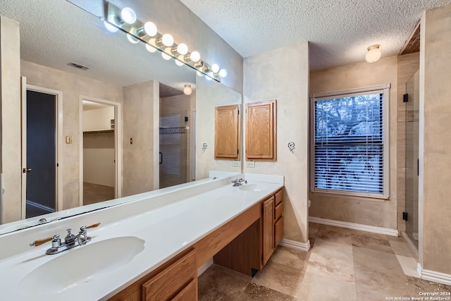 bathroom featuring vanity, a shower with shower door, and a textured ceiling