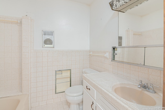 bathroom featuring toilet, vanity, a tub to relax in, and tile walls