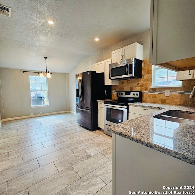 kitchen featuring pendant lighting, stainless steel appliances, lofted ceiling, and a healthy amount of sunlight