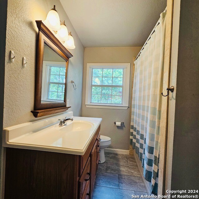 bathroom with toilet, vanity, a wealth of natural light, and a textured ceiling