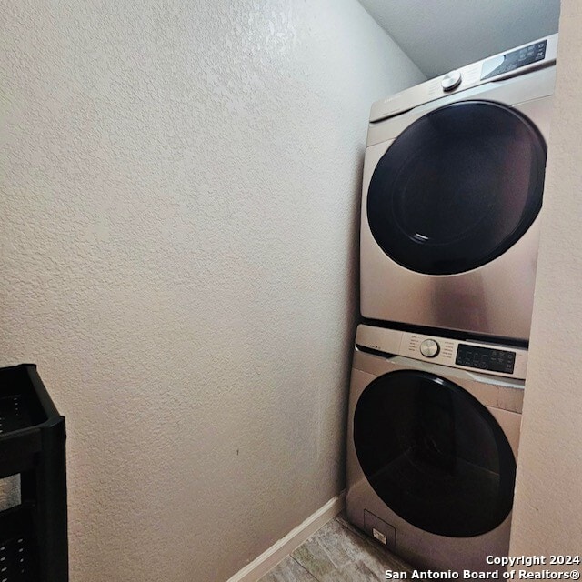 laundry room with stacked washer and dryer and light tile patterned floors