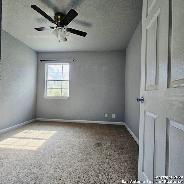 spare room featuring ceiling fan, a textured ceiling, and carpet