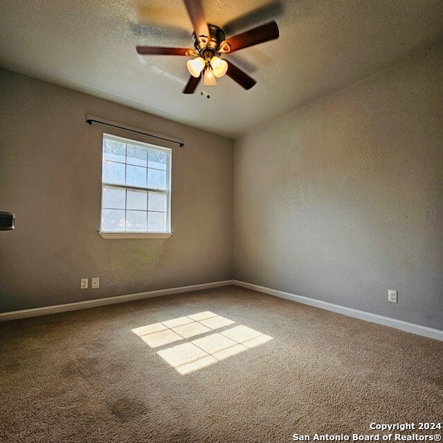 carpeted spare room featuring ceiling fan and a textured ceiling