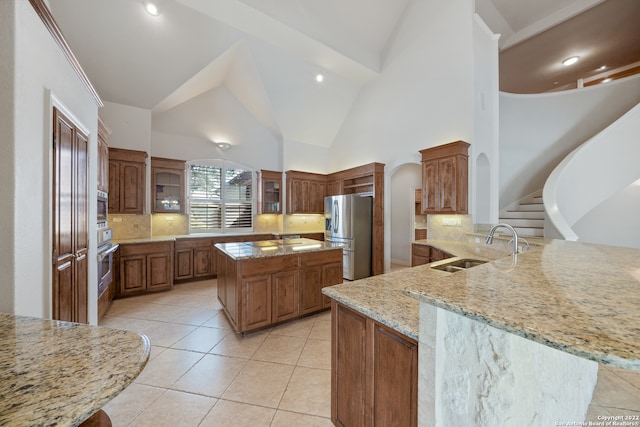 kitchen with stainless steel appliances, kitchen peninsula, sink, backsplash, and light stone countertops