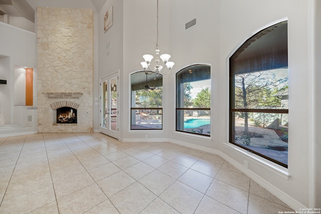 unfurnished dining area featuring plenty of natural light, light tile patterned flooring, a high ceiling, and an inviting chandelier