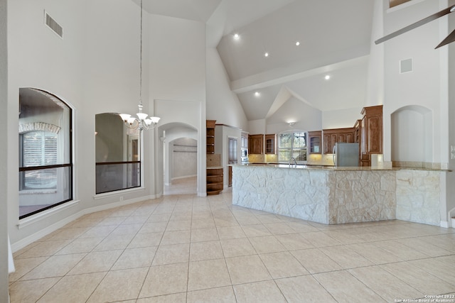 kitchen featuring stainless steel fridge, light tile patterned floors, high vaulted ceiling, an inviting chandelier, and kitchen peninsula