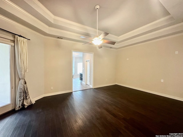 empty room featuring dark hardwood / wood-style floors, crown molding, and a tray ceiling