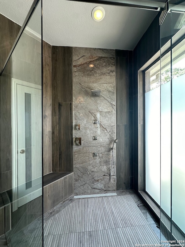 bathroom with tiled shower and a textured ceiling