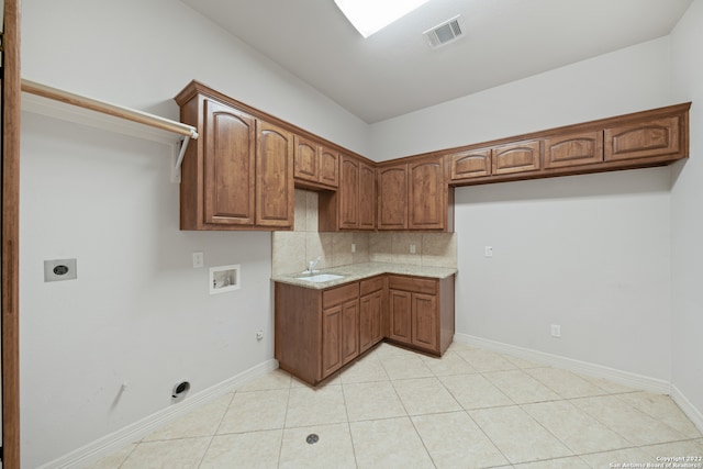 kitchen featuring decorative backsplash, light tile patterned floors, sink, and light stone countertops