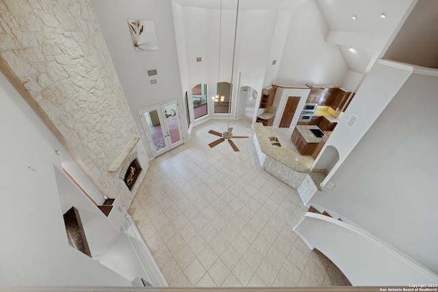 living room with a high ceiling, ceiling fan, and a fireplace