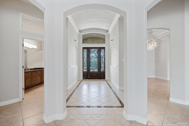 tiled entrance foyer with a notable chandelier, crown molding, and vaulted ceiling