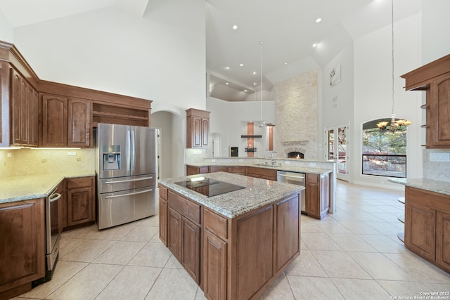 kitchen with stainless steel refrigerator with ice dispenser, hanging light fixtures, black electric cooktop, and high vaulted ceiling