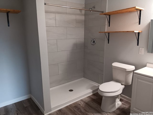 bathroom featuring hardwood / wood-style floors, vanity, toilet, and tiled shower