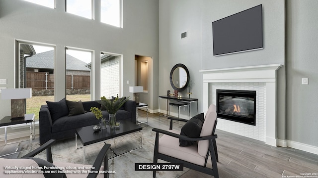 living room with hardwood / wood-style floors, a towering ceiling, and a tile fireplace