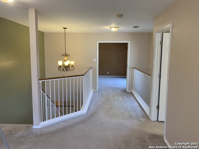 hall with an inviting chandelier and light colored carpet