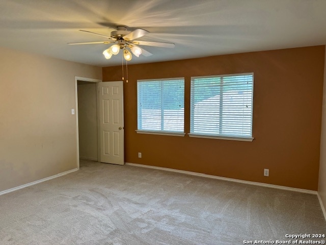 spare room with ceiling fan and light carpet