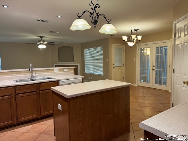 kitchen with a kitchen island with sink, hanging light fixtures, sink, and light tile patterned floors