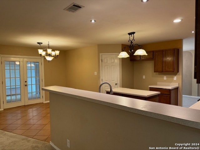 kitchen featuring french doors, light tile patterned flooring, pendant lighting, sink, and an inviting chandelier