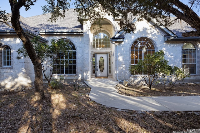 entrance to property featuring a shingled roof