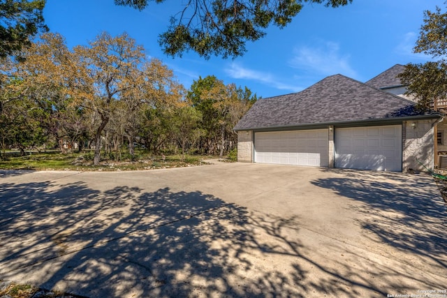 view of property exterior featuring driveway and a shingled roof