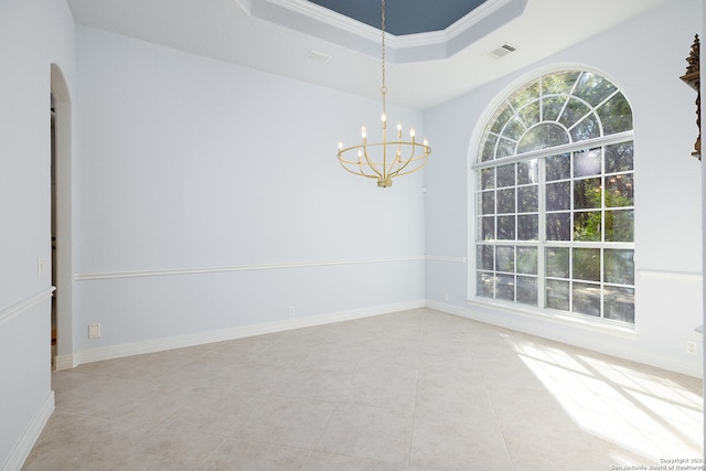 tiled spare room with a raised ceiling, ornamental molding, and an inviting chandelier