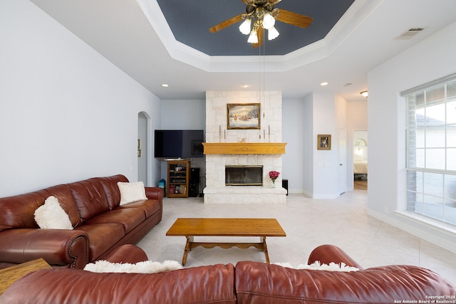 living room with light tile patterned floors, visible vents, a tray ceiling, a fireplace, and arched walkways