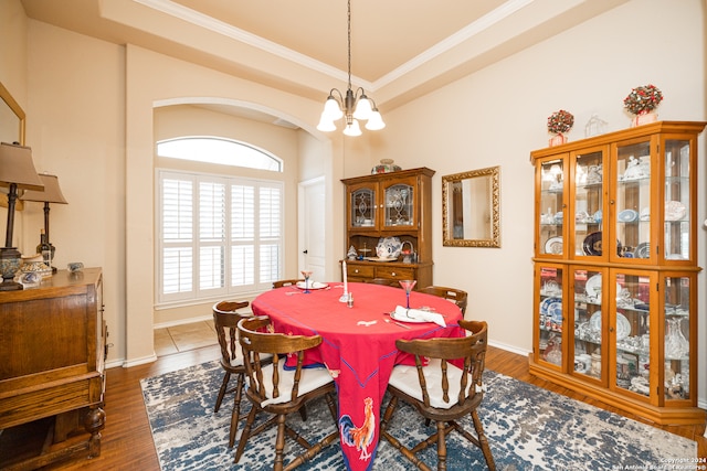 dining room with dark wood-type flooring, a tray ceiling, a notable chandelier, and crown molding